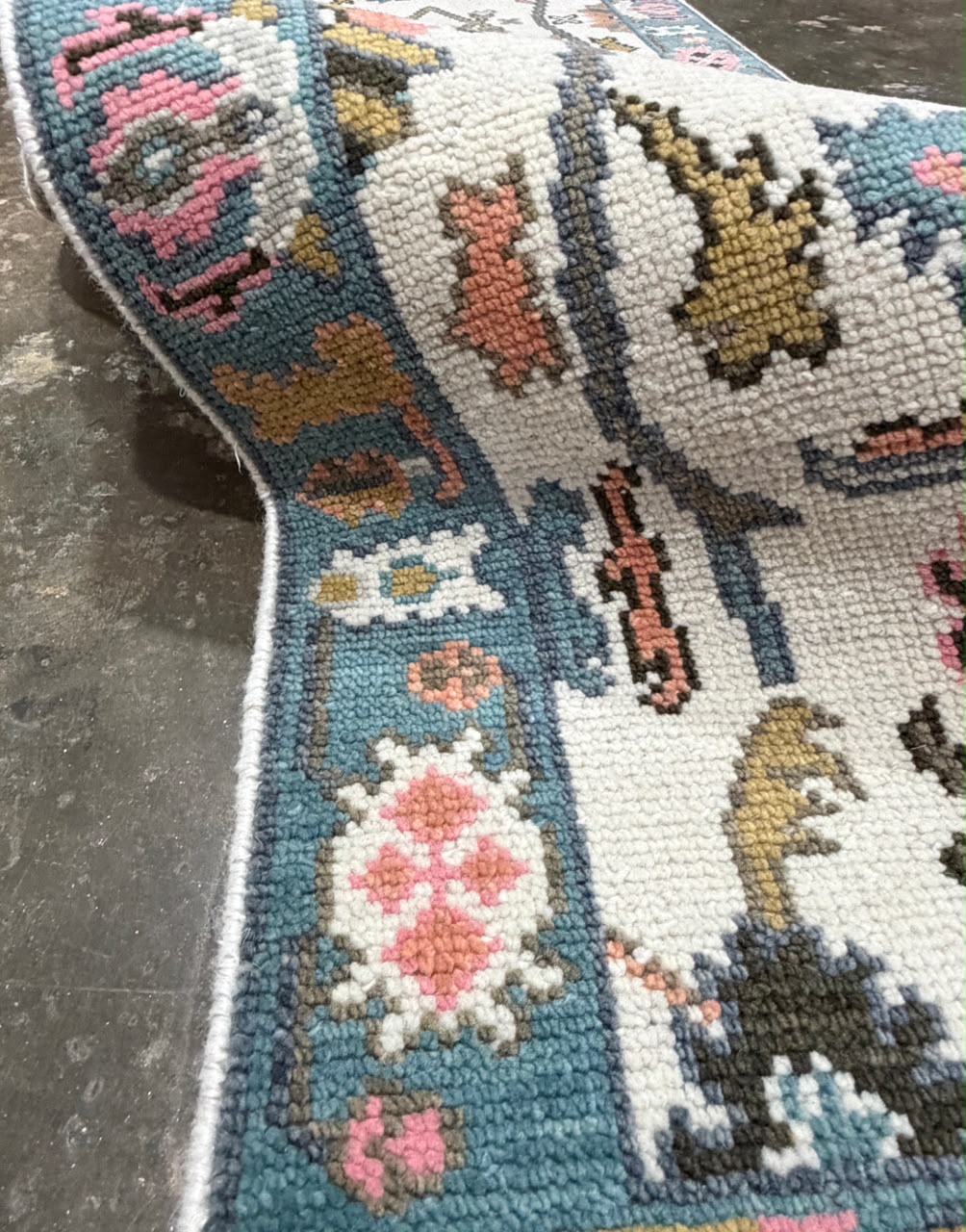 Traditional cream runner rug with geometric floral motifs and a dusty teal-blue border.