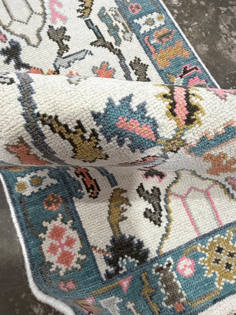 Close-up of a teal-blue floral runner border with pink, mustard and cream decorative motifs.
