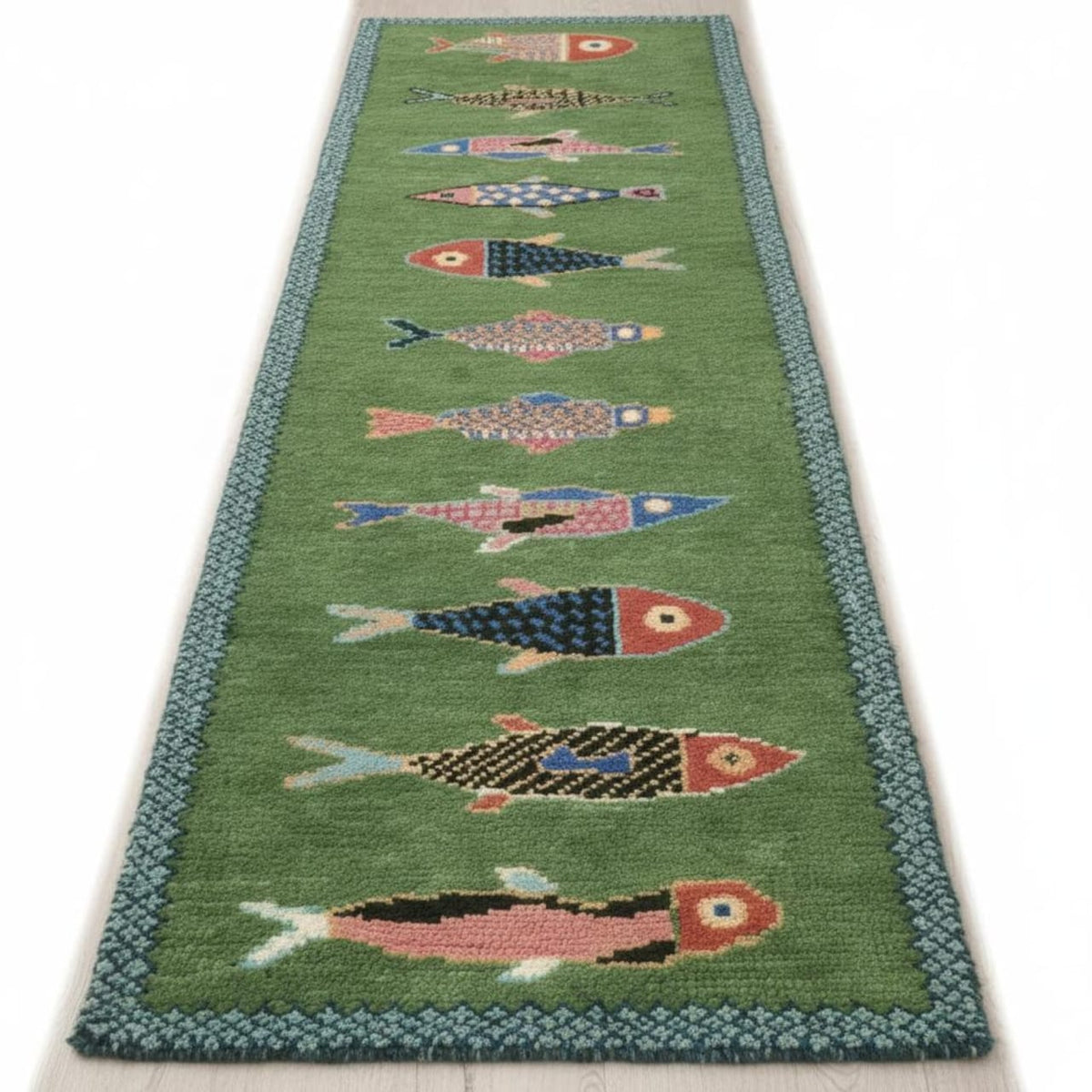 Full view of a green fish runner rug with colorful patterned fish and a blue geometric border.