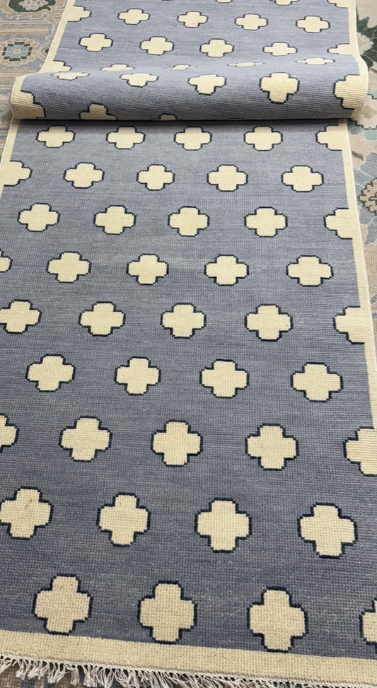 Rolled handmade wool rug showing low-pile construction and soft Scandinavian geometric design.