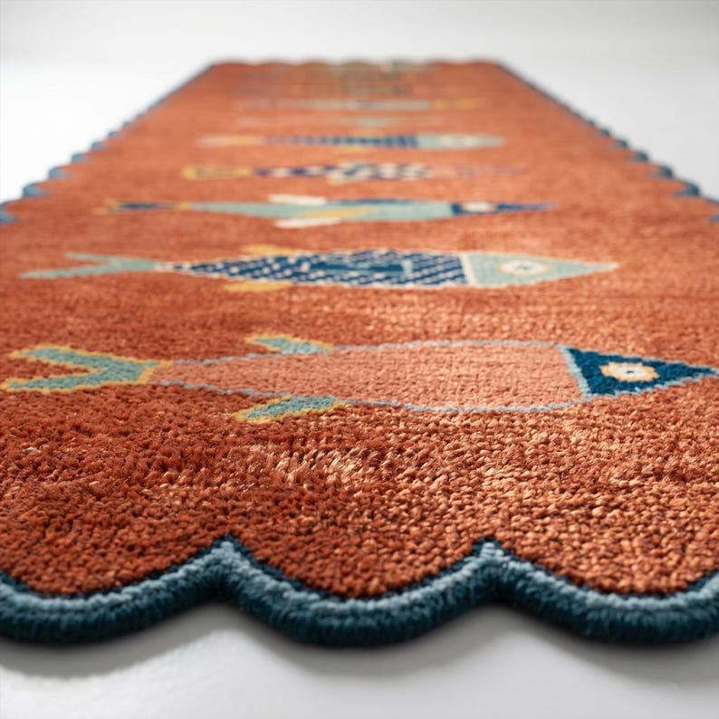 Long terracotta fish runner rug displaying repeated fish motifs and scalloped teal edges