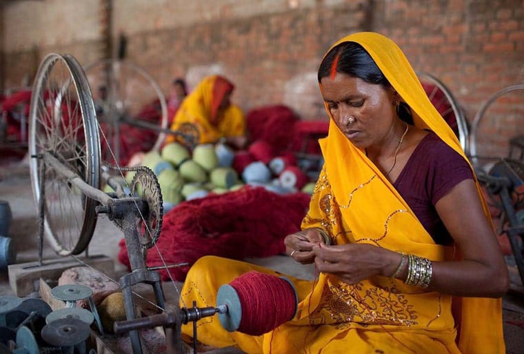 Artisan spinning natural wool yarn for handmade rugs at Oushakaura workshop