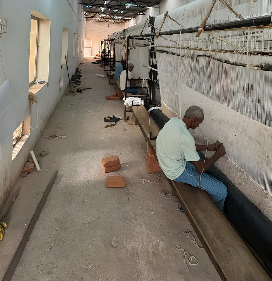 Handmade rug manufacturing workshop in India with skilled artisans weaving rugs at OUSHAKAURA