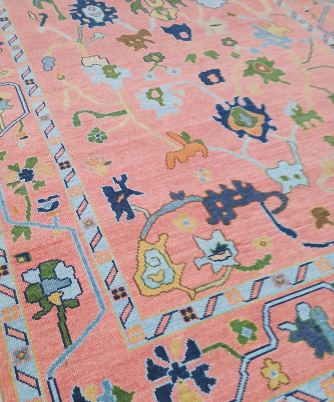 Close up of handwoven wool Oushak rug showing detailed floral and geometric motifs