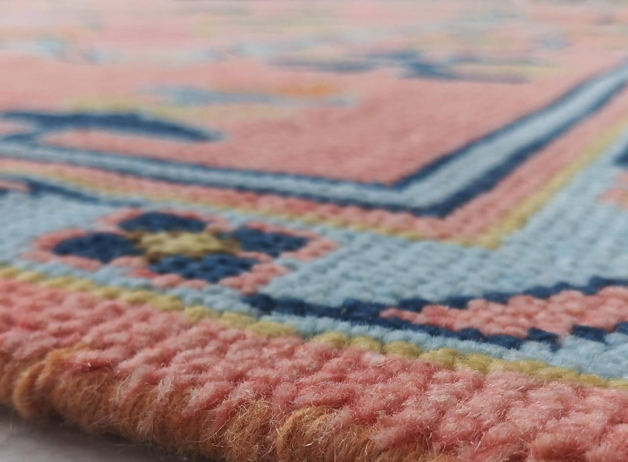 Close-up of a textured pink and blue rug with intricate patterns.