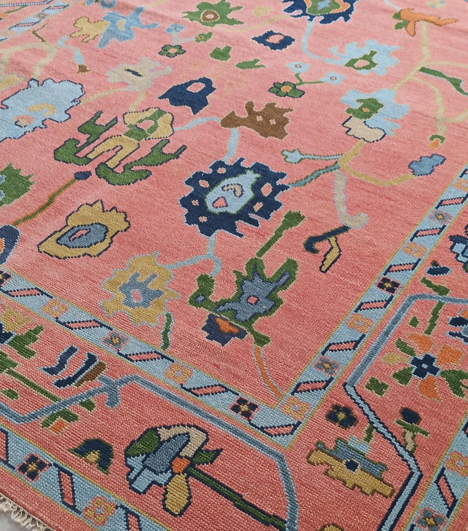 Decorative border detail of coral pink Oushak area rug with blue and mustard accents