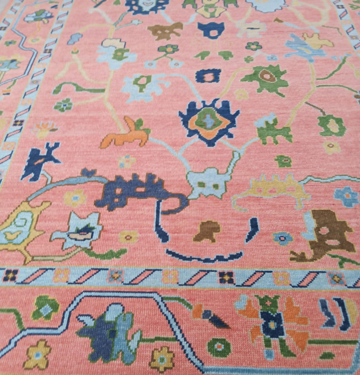 Colorful patterned rug with various shapes and designs on a pink background