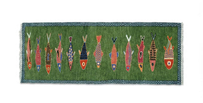 Decorative Oushakaura rug with colorful fish pattern on a green background