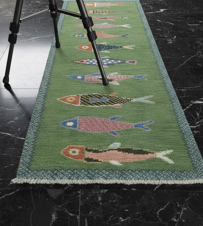 Green children's rug with fish pattern on a dark marble floor