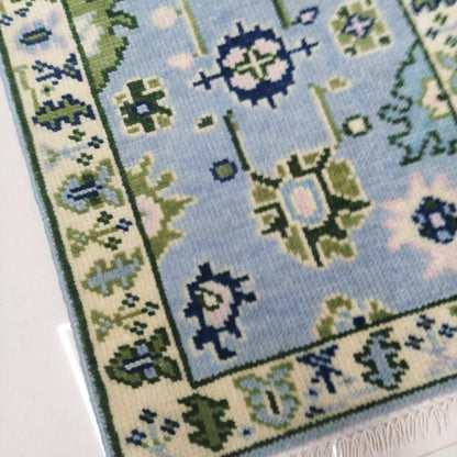 Close-up of a blue and green patterned rug with floral designs.