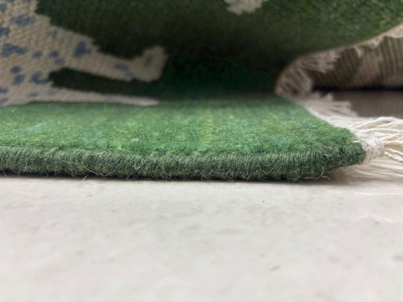 Hand-finished fringe edge on green wool leopard rug
