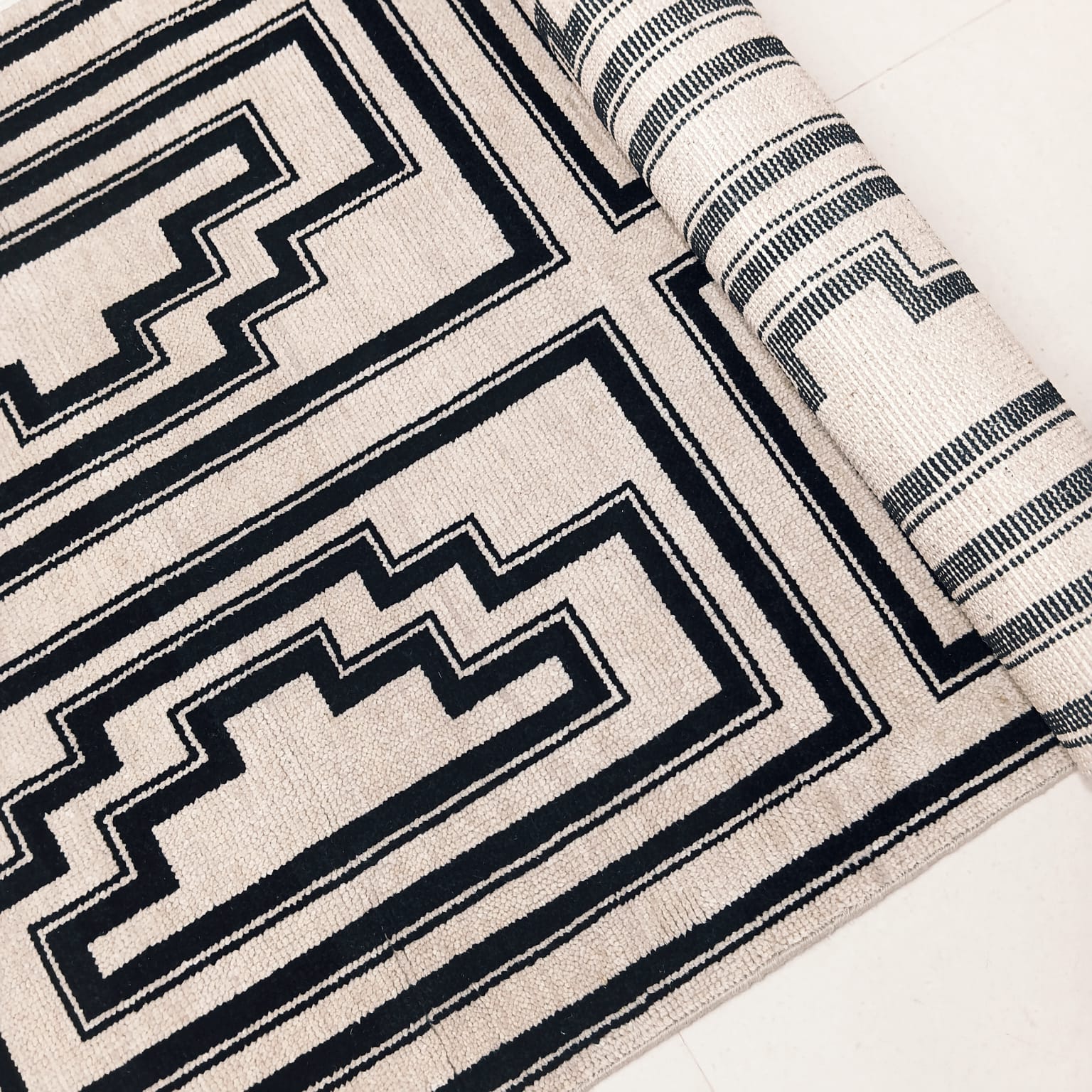 Angled view of black and ivory geometric handwoven wool rug
