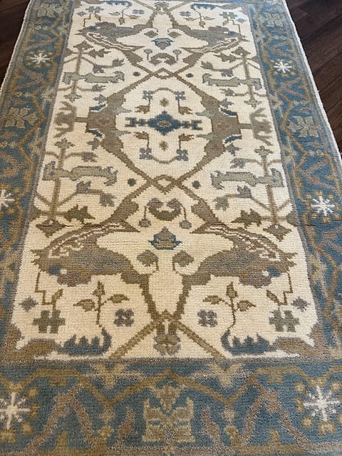 Close up of handmade tribal rug featuring animal motifs in ivory blue and taupe tones