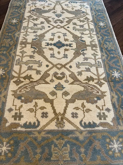 Close up of handmade tribal rug featuring animal motifs in ivory blue and taupe tones
