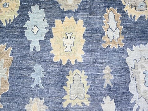 Close-up of handmade blue Oushak rug showing traditional floral pattern and wool texture.