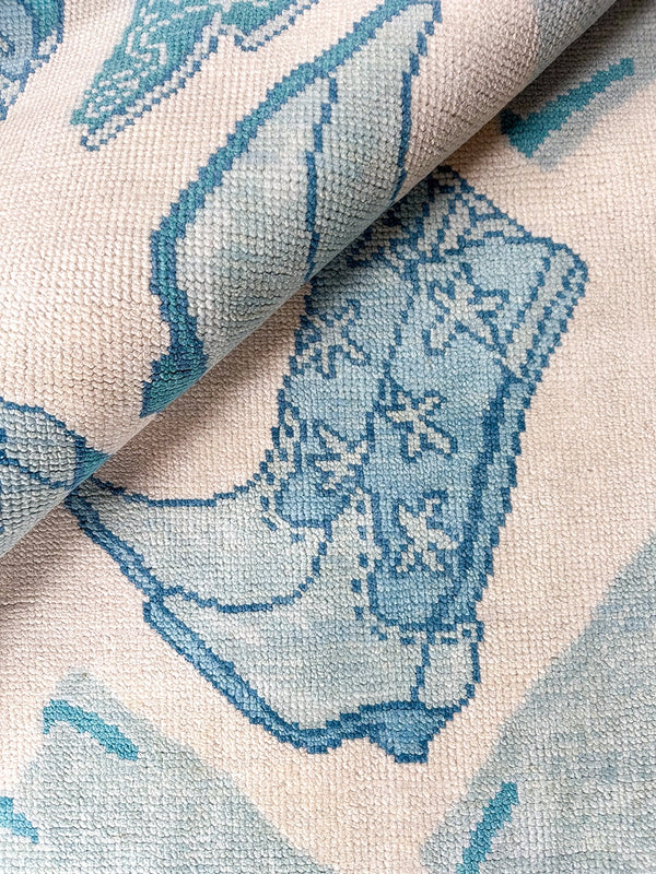 Blue and ivory handwoven rug with teal bird motif detail