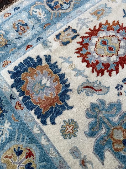 Close-up of a patterned rug with blue, red, and beige colors.