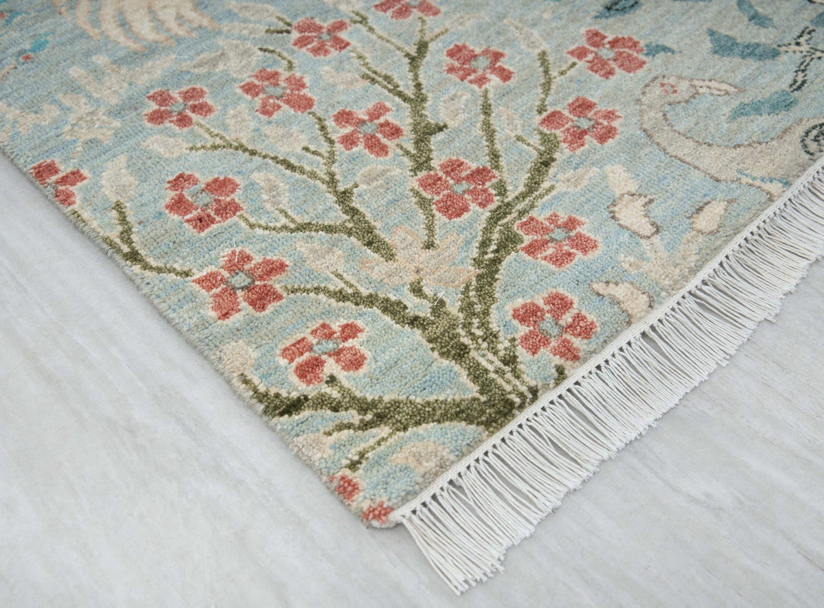 Corner of blue floral runner rug showing botanical pattern and decorative fringe