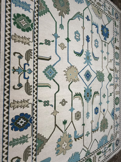 Close-up of blue and green geometric floral motifs on an ivory rug.
