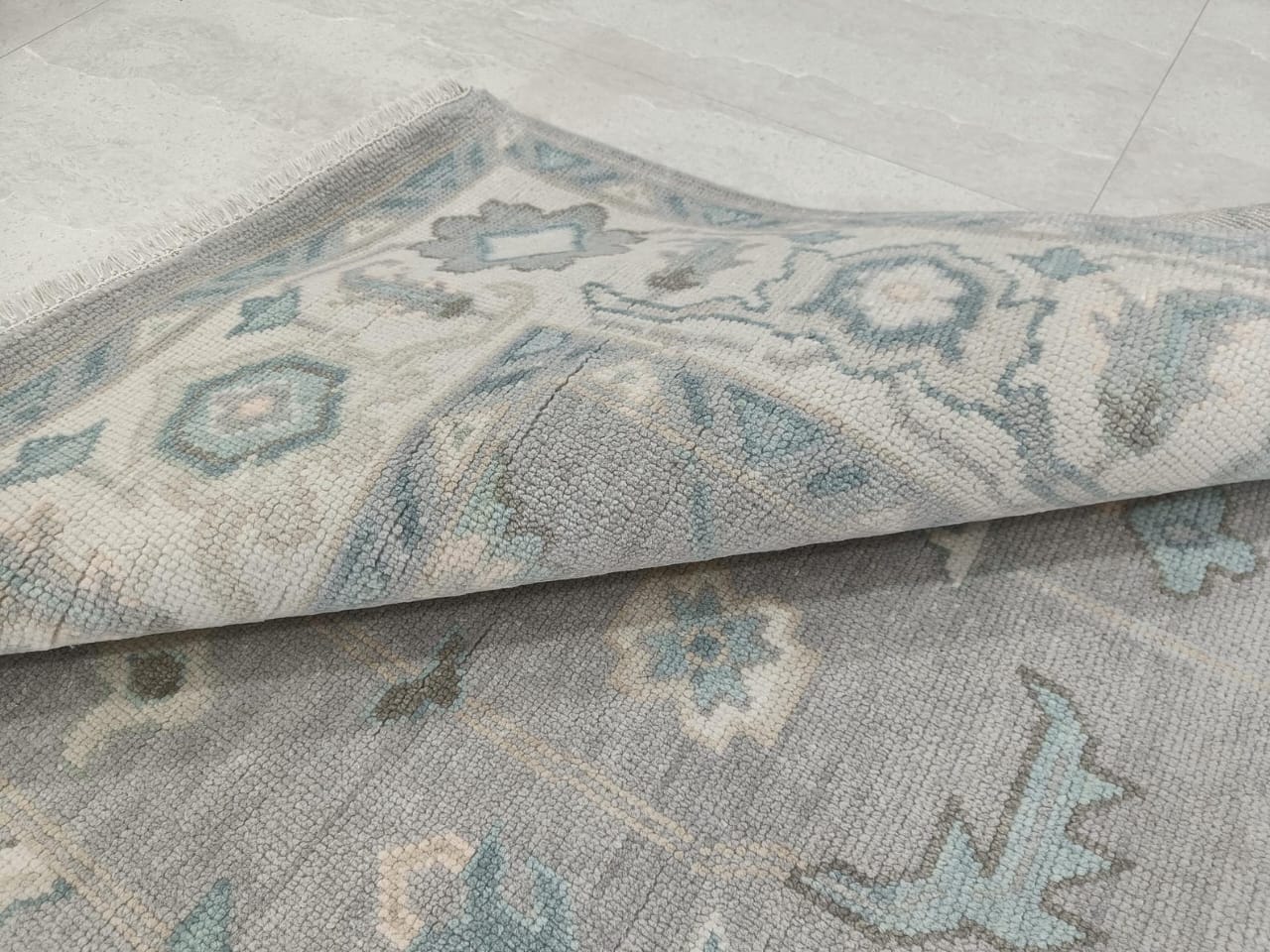 Folded corner detail showing thickness and texture of blue grey hand tufted rug