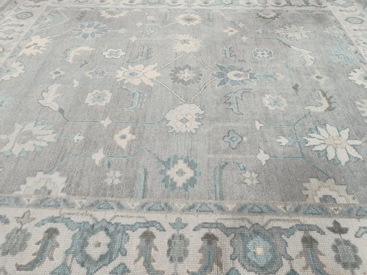 Center medallion detail of blue grey ivory Oushak style area rug