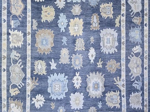 Traditional handmade blue Oushak rug featuring floral motifs and decorative ivory border.