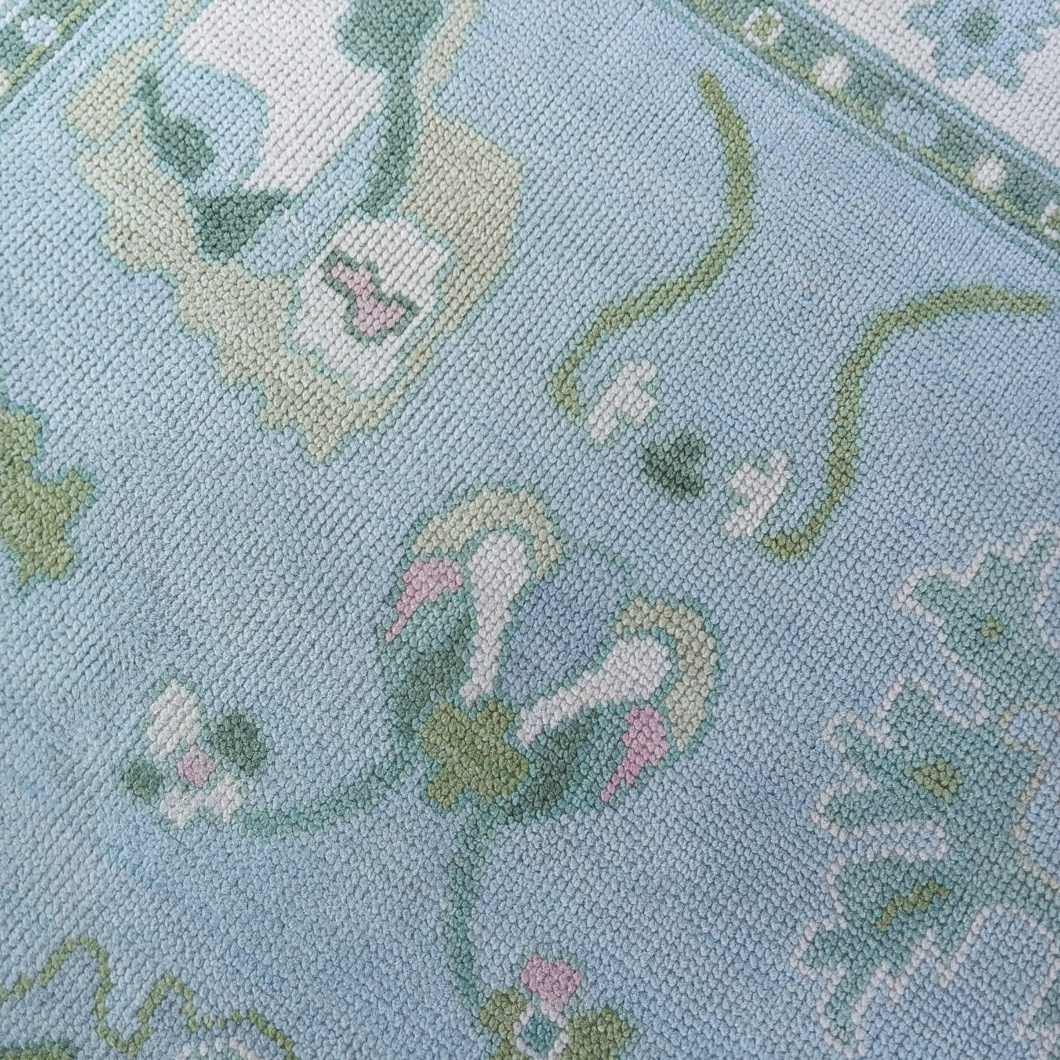 Close up of blue and ivory handwoven wool rug showing textured flatweave pile and detailed leaf grid pattern