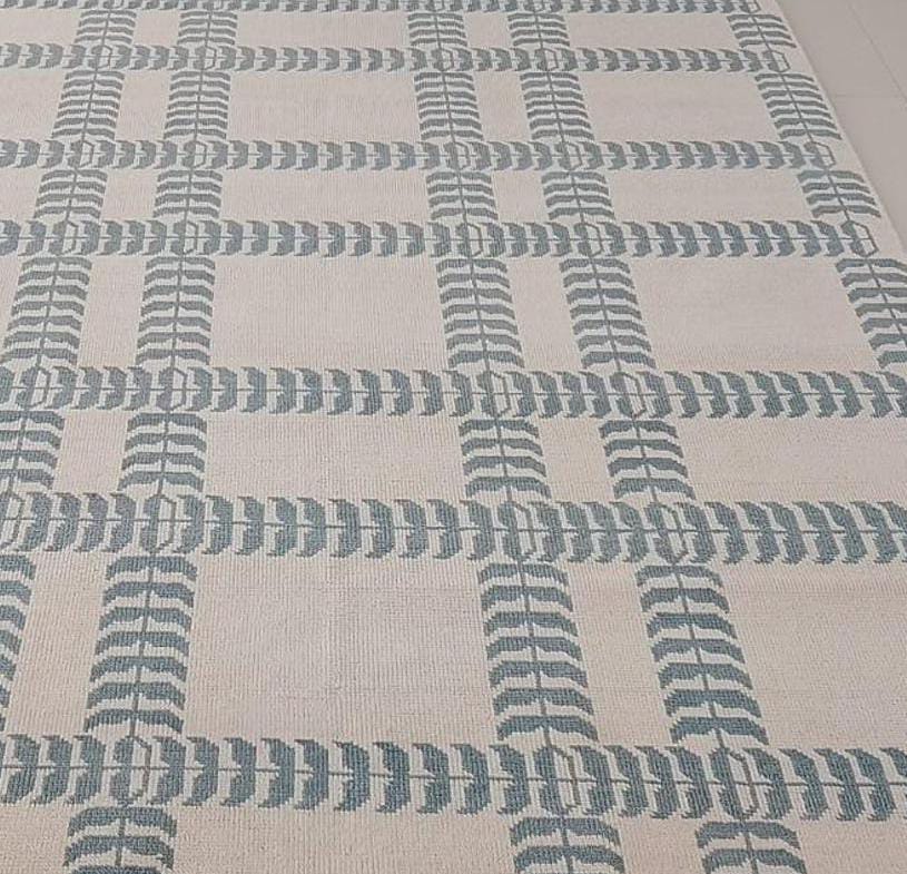 Close up of blue and ivory handwoven wool rug with modern geometric pattern and flatweave texture