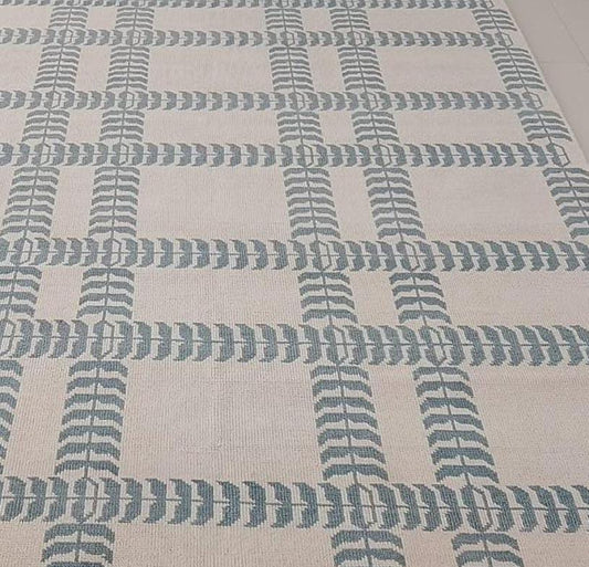 Close up of blue and ivory handwoven wool rug with modern geometric pattern and flatweave texture