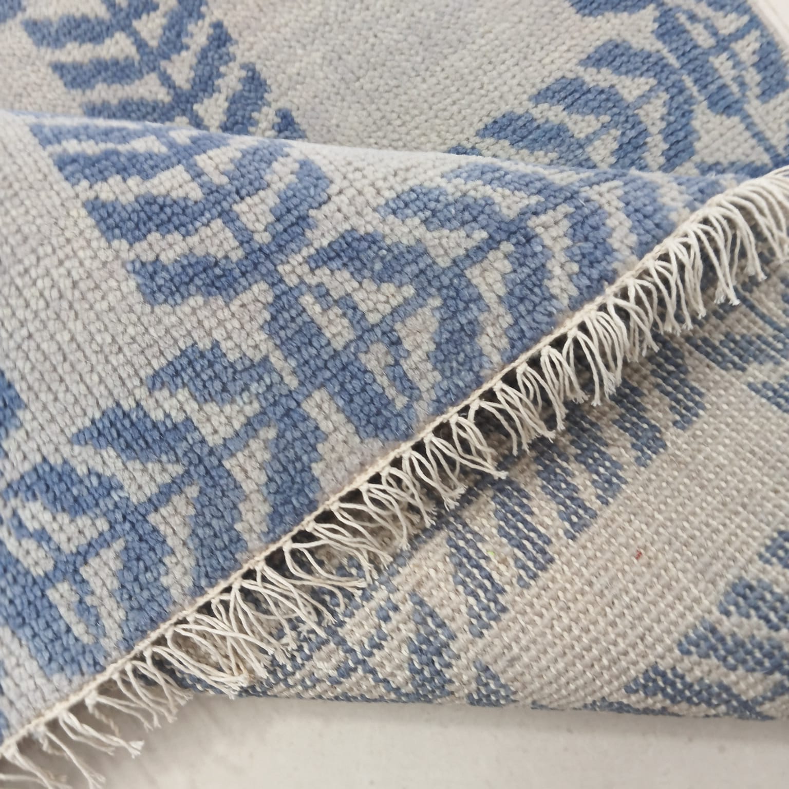 Folded modern wool rug in blue and ivory showing soft handwoven texture
