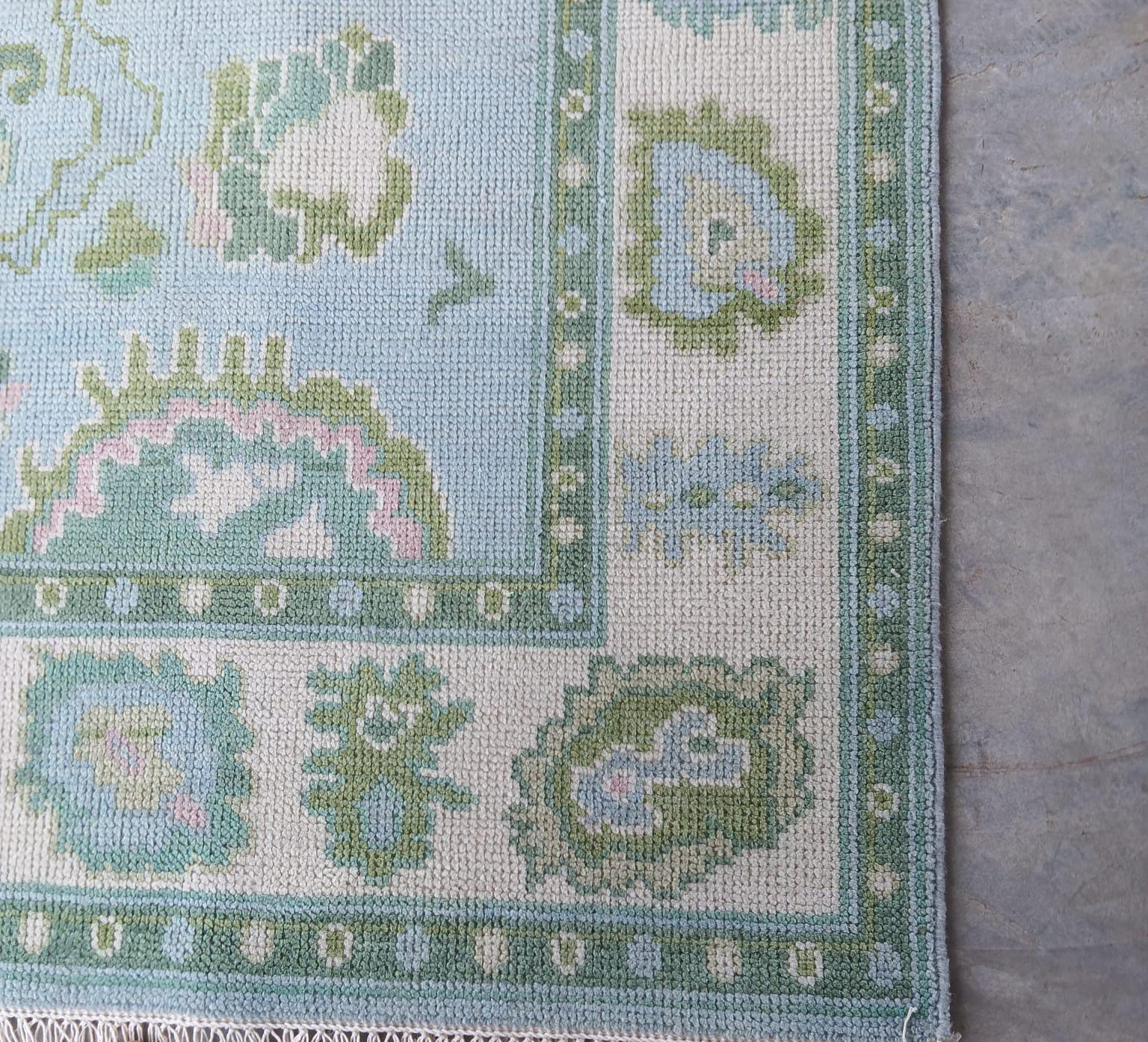 Detailed border pattern of blue and ivory handwoven wool rug with symmetrical leaf motif