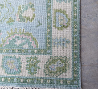 Detailed border pattern of blue and ivory handwoven wool rug with symmetrical leaf motif