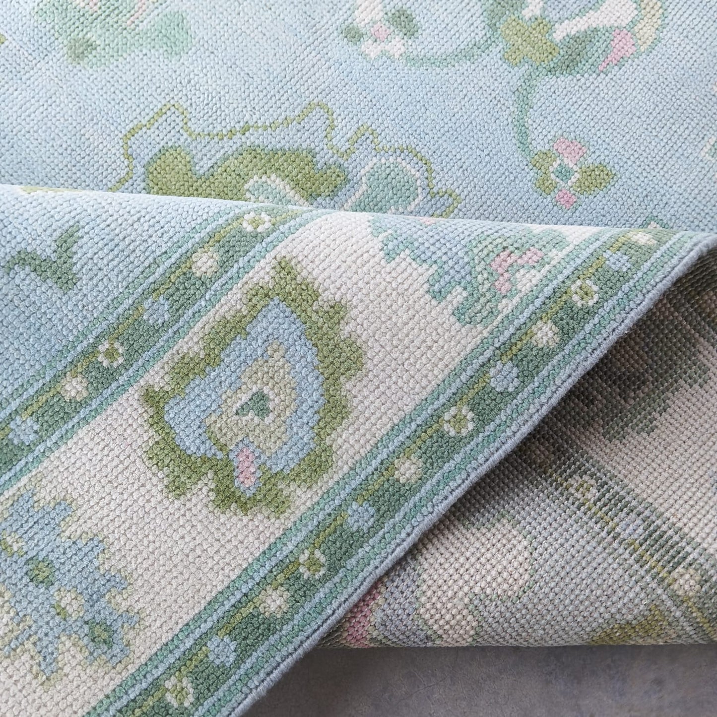 Folded blue and ivory handmade wool rug highlighting soft texture and artisan flatweave construction