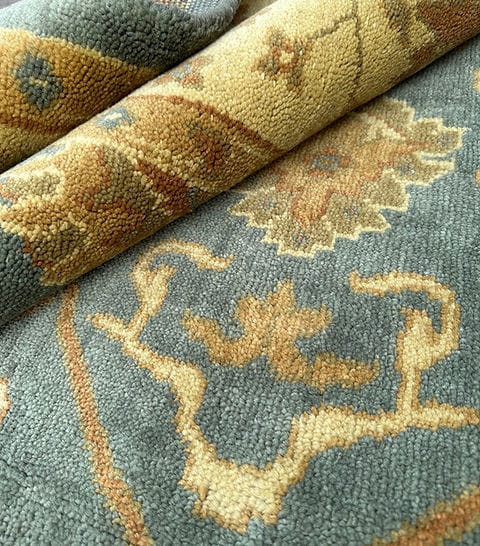 Handmade Blue Oushak Rug featuring traditional floral motifs, ivory border, and premium wool craftsmanship