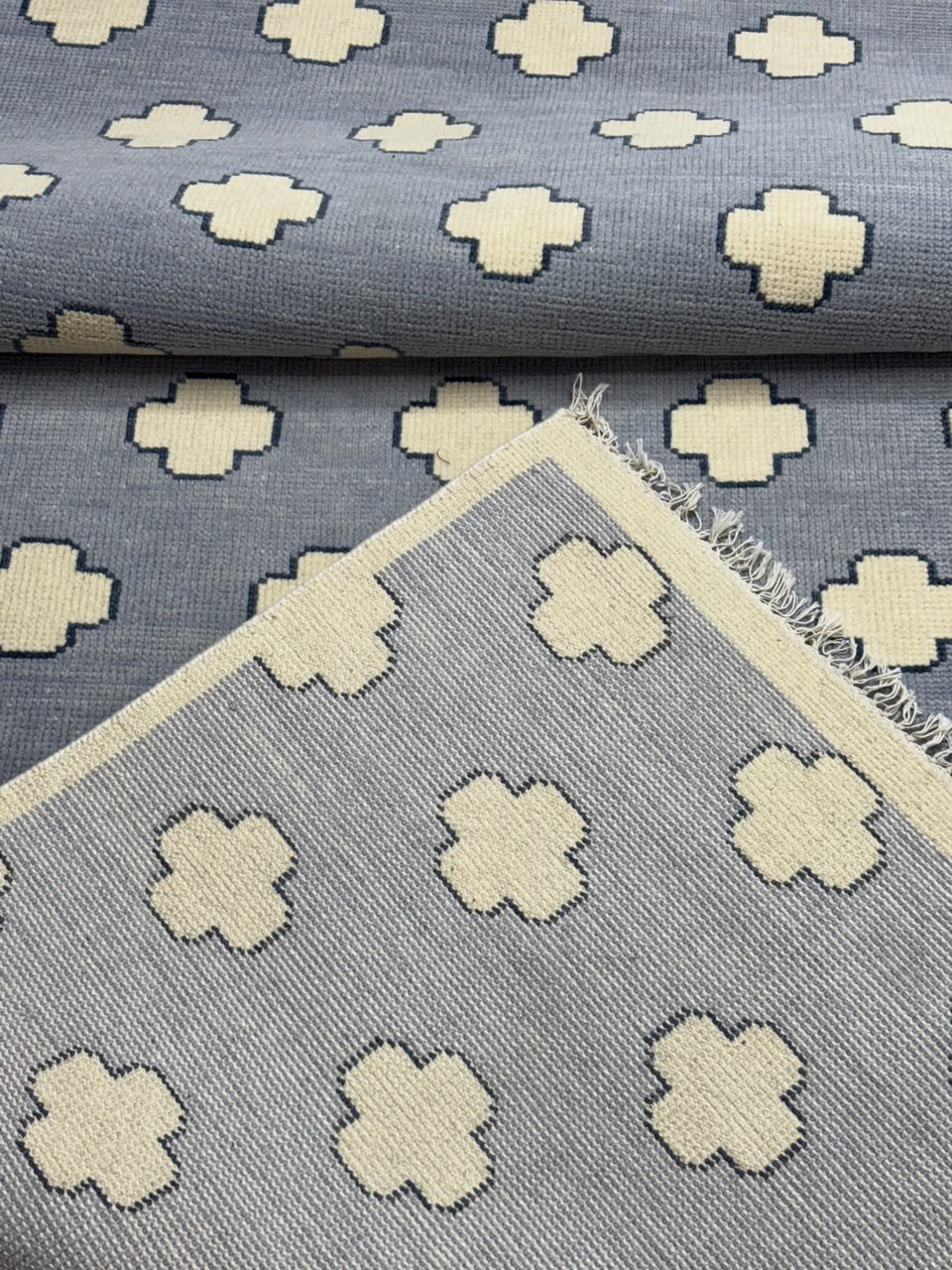 Folded corner of a handmade dusty blue wool rug highlighting clean edge finishing and craftsmanship.
