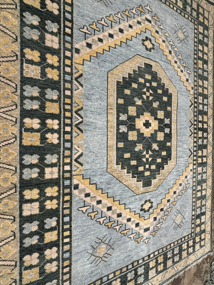 Angled view of handmade blue tribal Oushak rug highlighting geometric medallion and traditional border details.