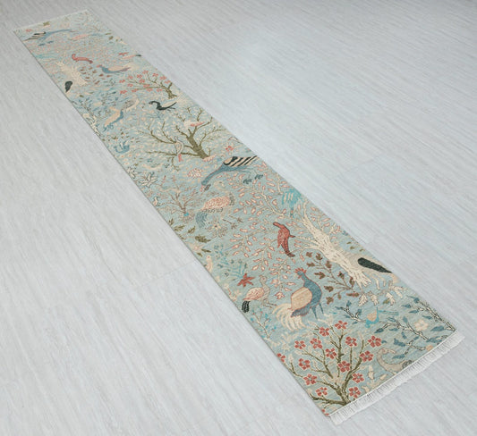 Angled view of blue vintage bird runner rug with floral botanical design and fringed ends
