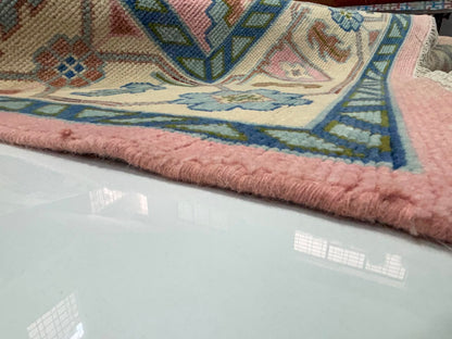 Side profile showing the low-pile thickness of a handmade blush pink Oushak wool rug.