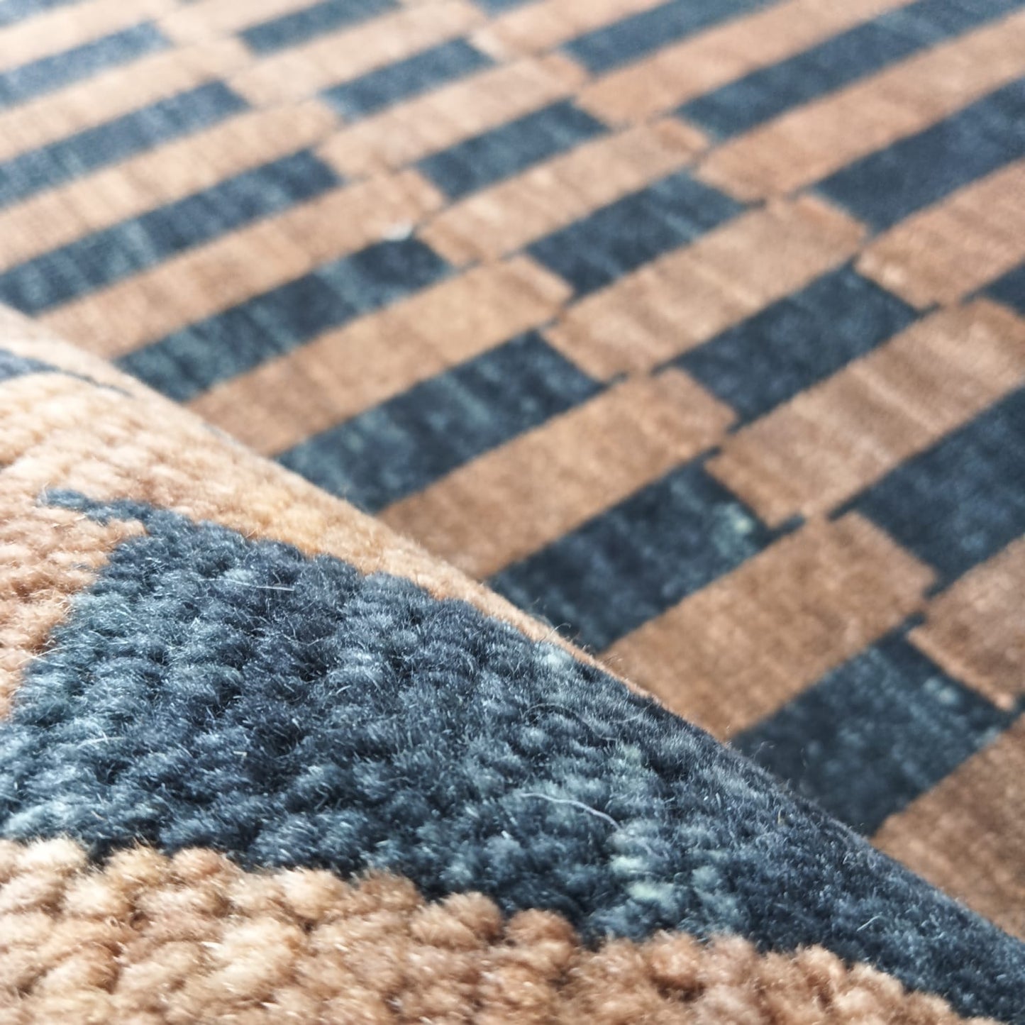 Folded edge detail of brown and black handwoven wool rug
