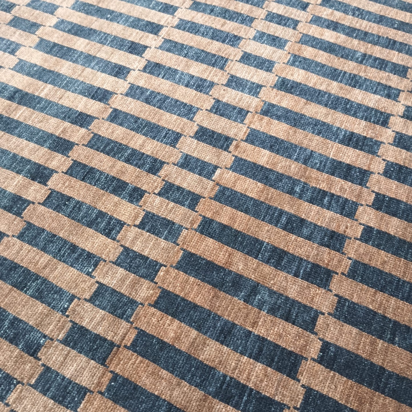 Striped pattern detail on brown and black handwoven wool rug
