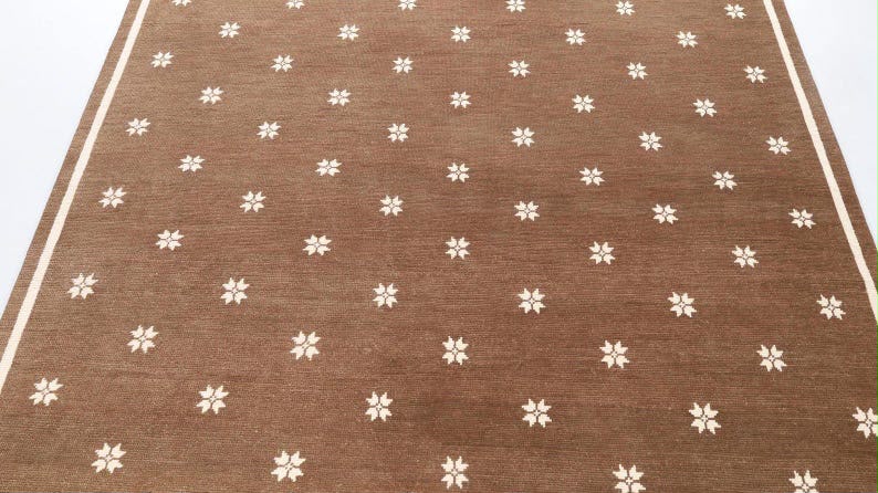Brown rug with small ivory floral motifs and a contrasting border.