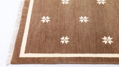 Overall view of a brown rug with ivory floral motifs and border.