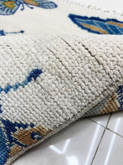 Close-up of handmade butterfly rug featuring colorful butterfly motifs on ivory background