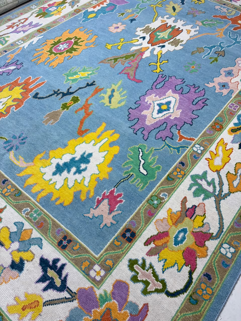 Angled view of handmade contemporary Oushak rug featuring vibrant botanical artwork