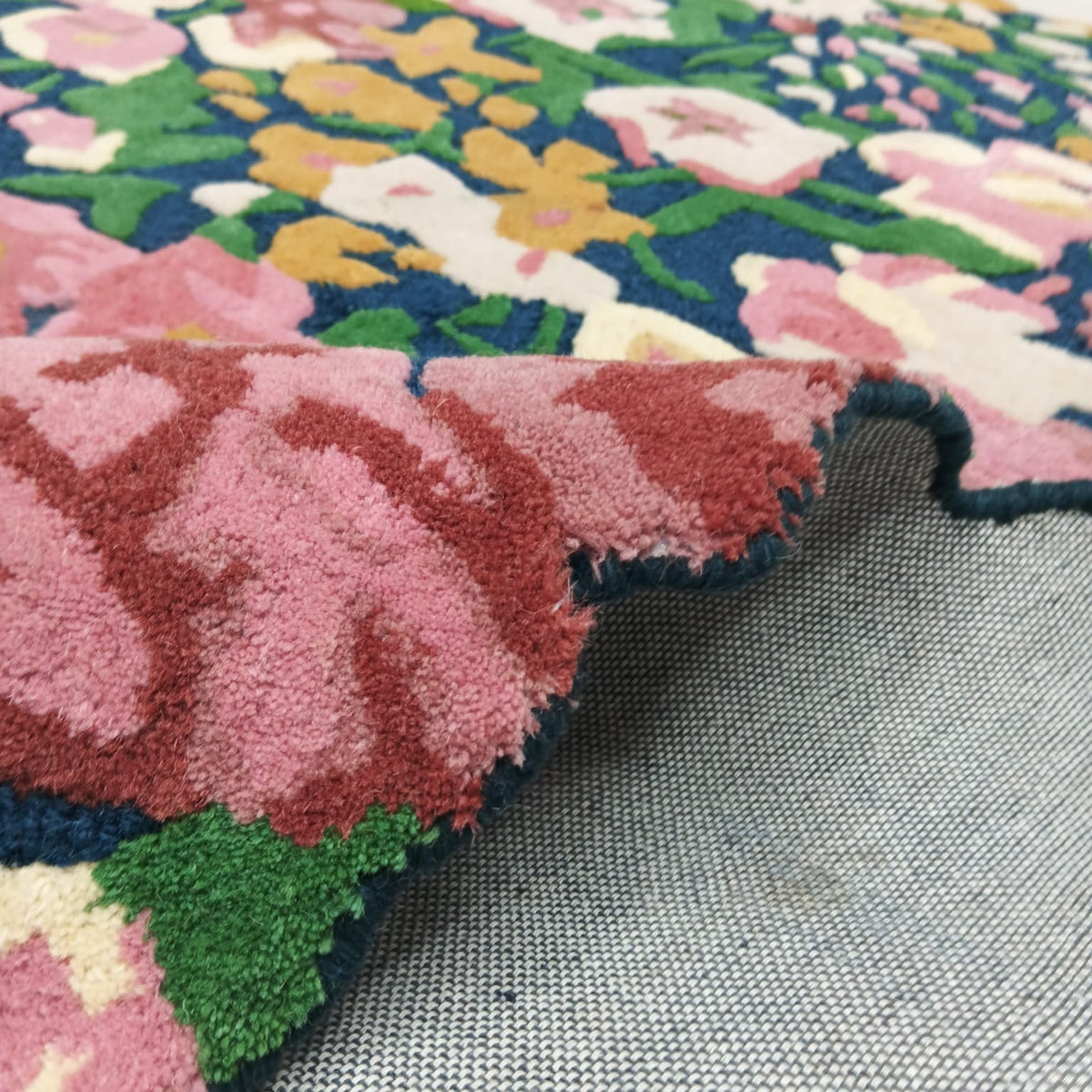Raised floral rug edge showing pink burgundy cream and navy pile