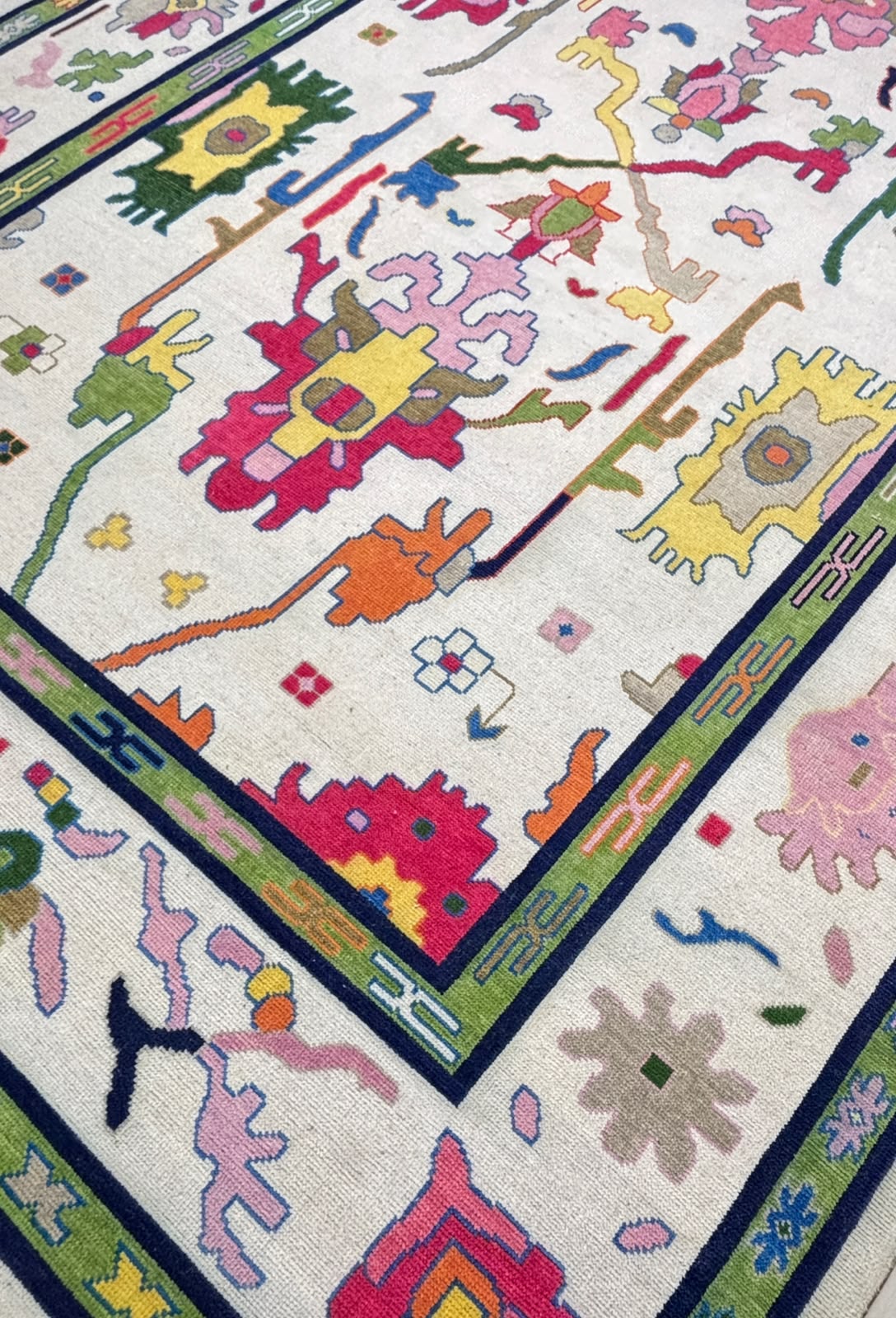 Diagonal view of a handcrafted colorful Nordic wool rug with modern folk art pattern and decorative border.