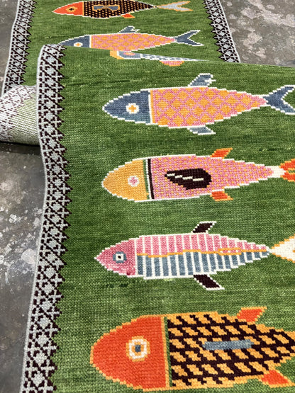 Close-up of the medium pile wool texture and colourful details of a hand-knotted green rug