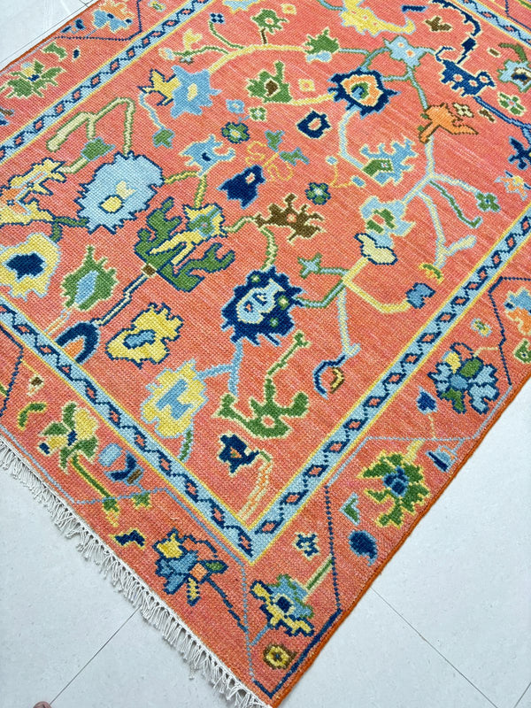 Handmade coral Oushak rug with colorful floral motifs and vintage Turkish inspired design