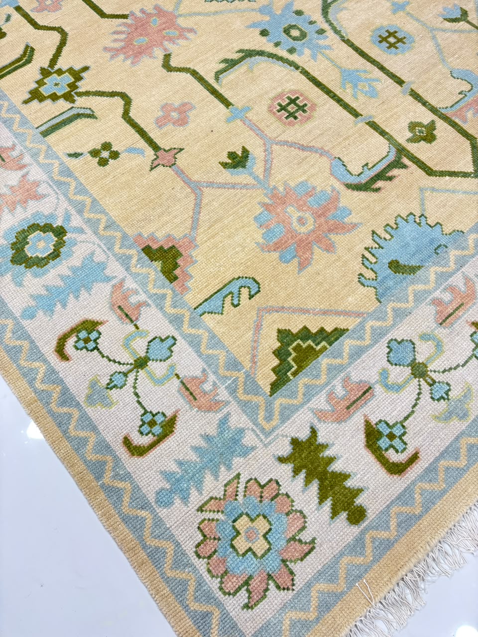 Corner detail of handmade cream and blue Oushak area rug.