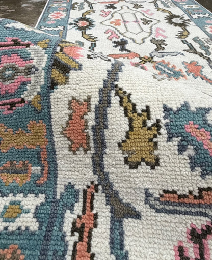 Close-up of a teal-blue floral runner border with pink, mustard and cream decorative motifs.